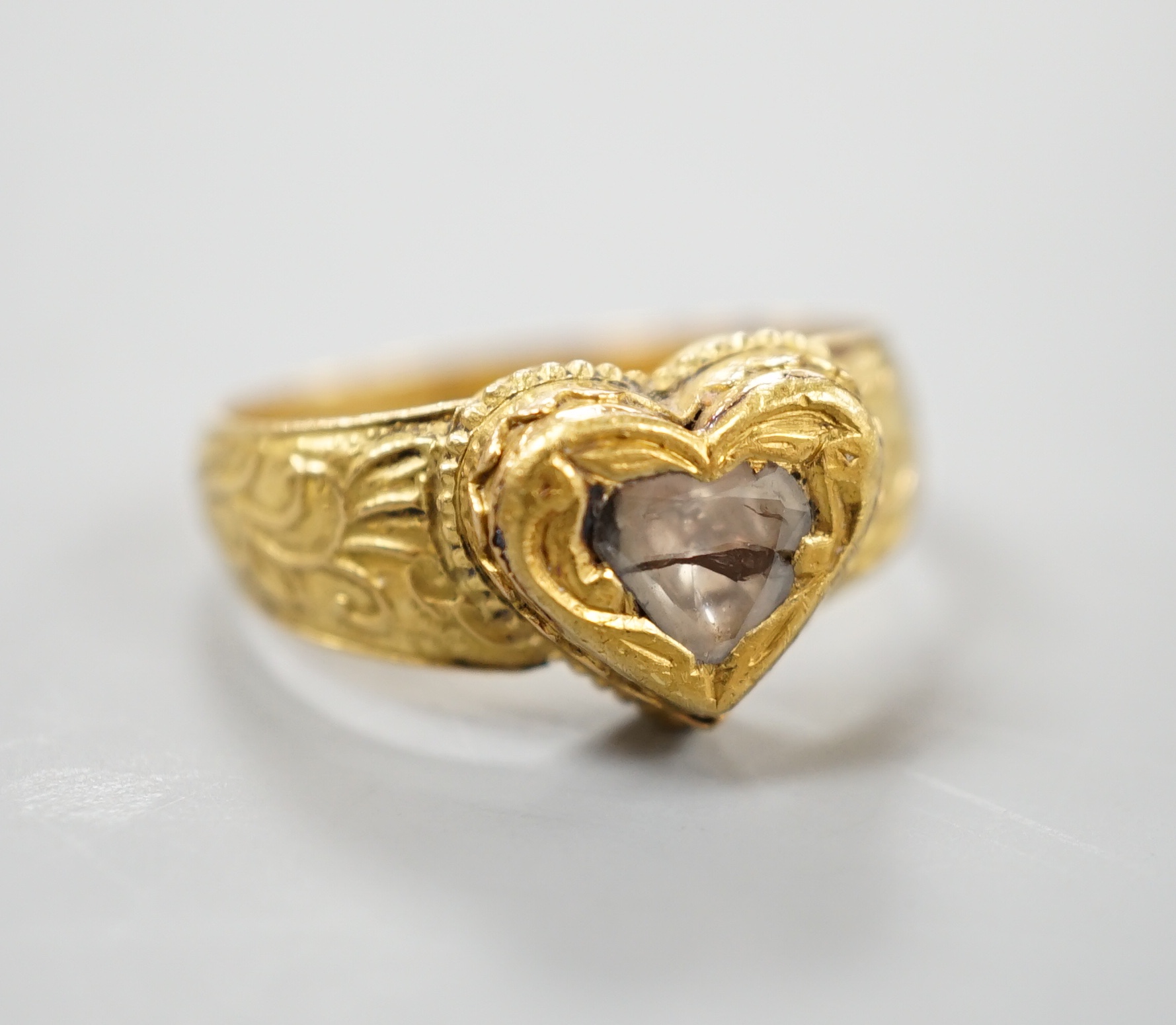 An Indian yellow metal and heart shaped diamond set ring, with engraved shank, size O, gross weight 6.2 grams, (crack to stone).